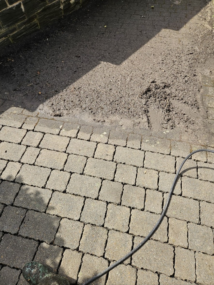 Block paving part-way through a pressure wash, with the clean line clearly visible